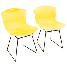 two yellow chairs sitting next to each other on top of a white surface with black legs