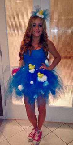 a woman in a blue dress and pink shoes standing next to a door with rubber ducks on it