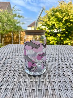 a glass with a straw in it sitting on top of a wicker table outside