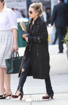 the woman is walking down the street with her hand in her pocket and holding a book