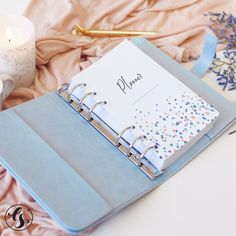 a blue notebook sitting on top of a table next to a candle and some flowers