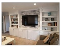 a living room with built in bookshelves and a flat screen tv mounted on the wall