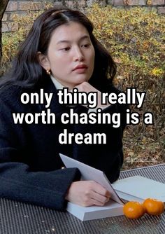 a woman sitting at a table with an orange in front of her and the words, only thing really worth chasing is a dream