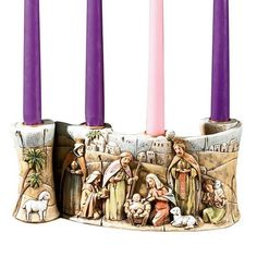 three candles with nativity scene on them and purple candlesticks in the middle