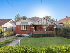 a red brick house sitting on top of a lush green yard