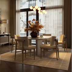 a dining room table with chairs and a vase filled with flowers sitting on top of it