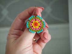 a person holding a colorful beaded object in their hand and wearing it as a ring