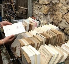 there are many books that are stacked on top of each other and being held by someone's hand