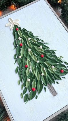 a christmas tree made out of green leaves and red berries is displayed on a canvas