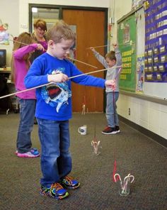 two children are playing with kites in the classroom, and one child is trying to fly