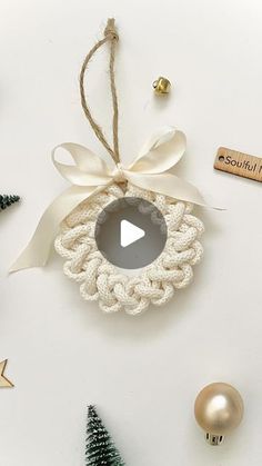 an ornament hanging from a string next to christmas decorations and ornaments on a white surface