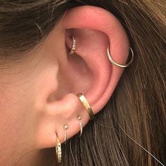 a woman wearing three different types of ear piercings on her left side of the ear