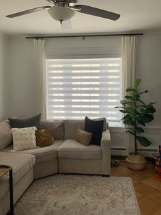 a living room with a sectional couch, rug and ceiling fan in the middle of it