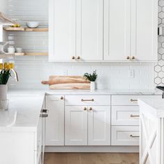 a kitchen with white cabinets and wood flooring is pictured in this image, there are yellow tulips on the counter