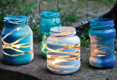 three mason jars with string lights in them sitting on the ground next to some grass