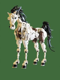 a lego horse that is made out of white and black plastic parts on a green background