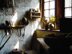 an old kitchen with many pots and pans on the wall next to a window