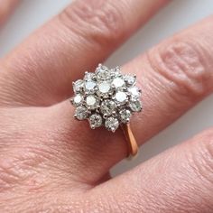 a woman's hand with a ring on top of her finger and an engagement ring in the middle