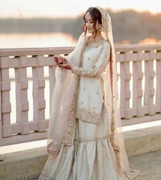 a woman in a wedding dress standing on a bridge