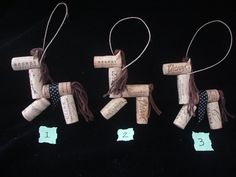 three wine corks with numbers on them are hanging from twine strings in the shape of horses