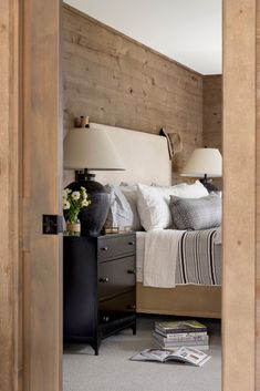 a bedroom with wood paneling and white bedding