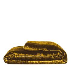 two gold velvet pillows sitting on top of each other in front of a white background