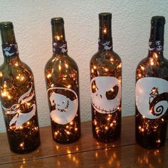 three wine bottles with lights in them sitting on top of a wooden table next to each other