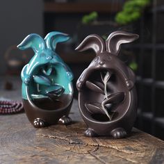 two ceramic rabbits sitting on top of a wooden table