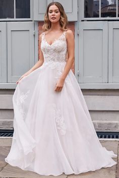 a woman in a white wedding dress standing outside