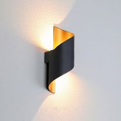 a black and yellow wall light on a white wall