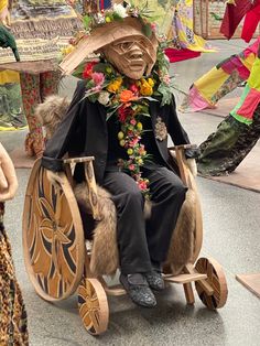 a man sitting in a horse drawn carriage decorated with flowers and feathers, wearing a sombrero