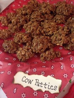 a table topped with lots of granola next to a sign that says cow patties