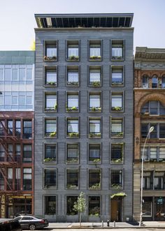 an apartment building with many windows and plants on the roof