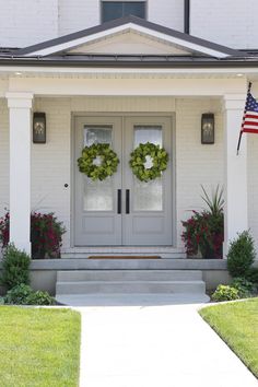 two wreaths on the front door of a white house