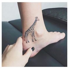 a woman's foot with a giraffe tattoo on it