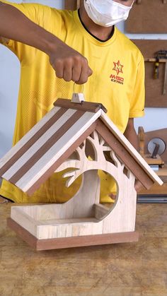 a man wearing a face mask is making a birdhouse