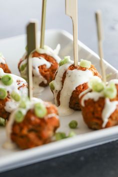 several appetizers with toothpicks in them sitting on a white platter