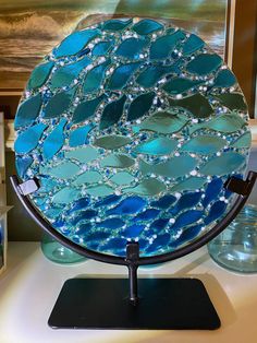 a blue and green plate sitting on top of a table next to a glass vase