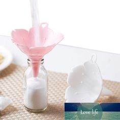 there is a small glass bottle with sand in it and a pink flower sticking out of the top