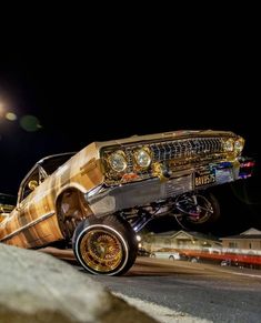 an old car is parked on the side of the road at night with its lights on