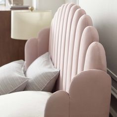 an upholstered headboard on a bed with white pillows and a lamp in the background