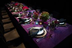 the table is set with purple linens and place settings