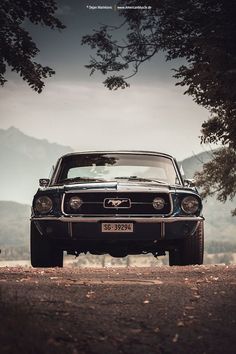 an old mustang is parked on the side of the road