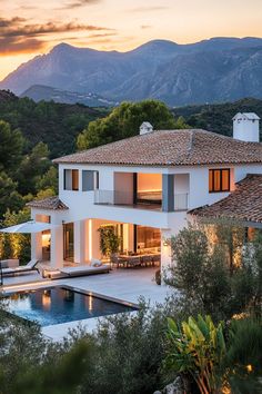 a large white house with a pool in front of it and mountains in the background