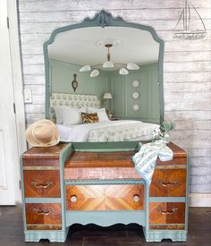 a bedroom with a bed, dresser and hat on it's headboard in front of a mirror