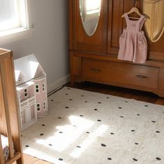 a baby's room with a dresser, mirror and toy house on the floor