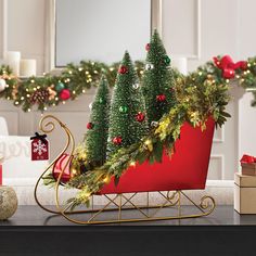 a red sleigh with christmas trees and presents on the table next to it