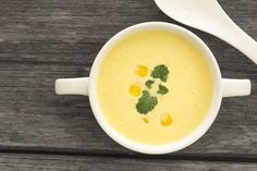 there is a bowl of soup with broccoli on the top and spoon next to it