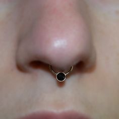 a close up view of a nose with a black stone in it's center