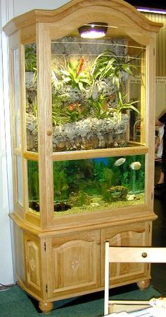 a fish tank sitting on top of a wooden cabinet next to a table with chairs